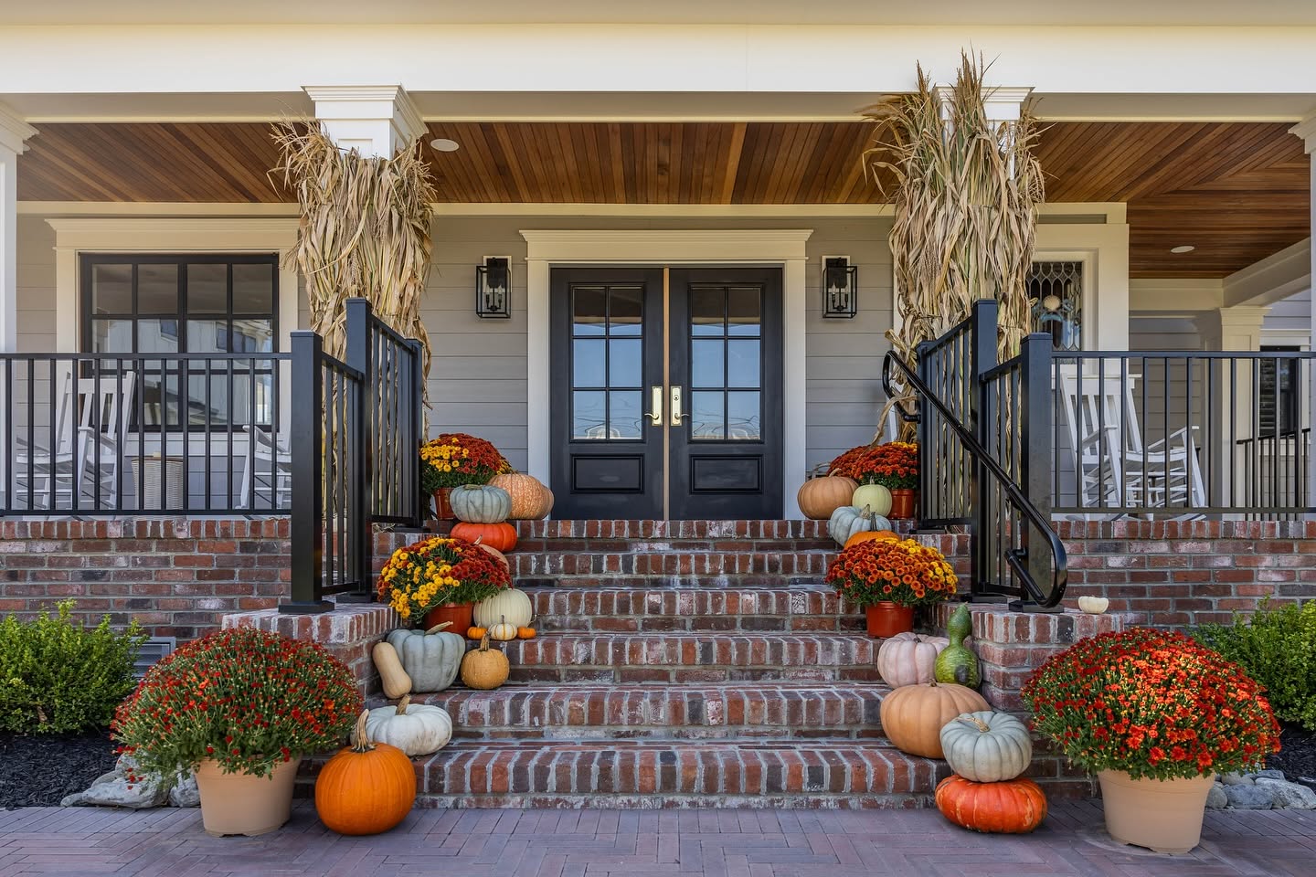 Fall porch at The Hen Houses decorated with pumpkins, mums, and corn stalks