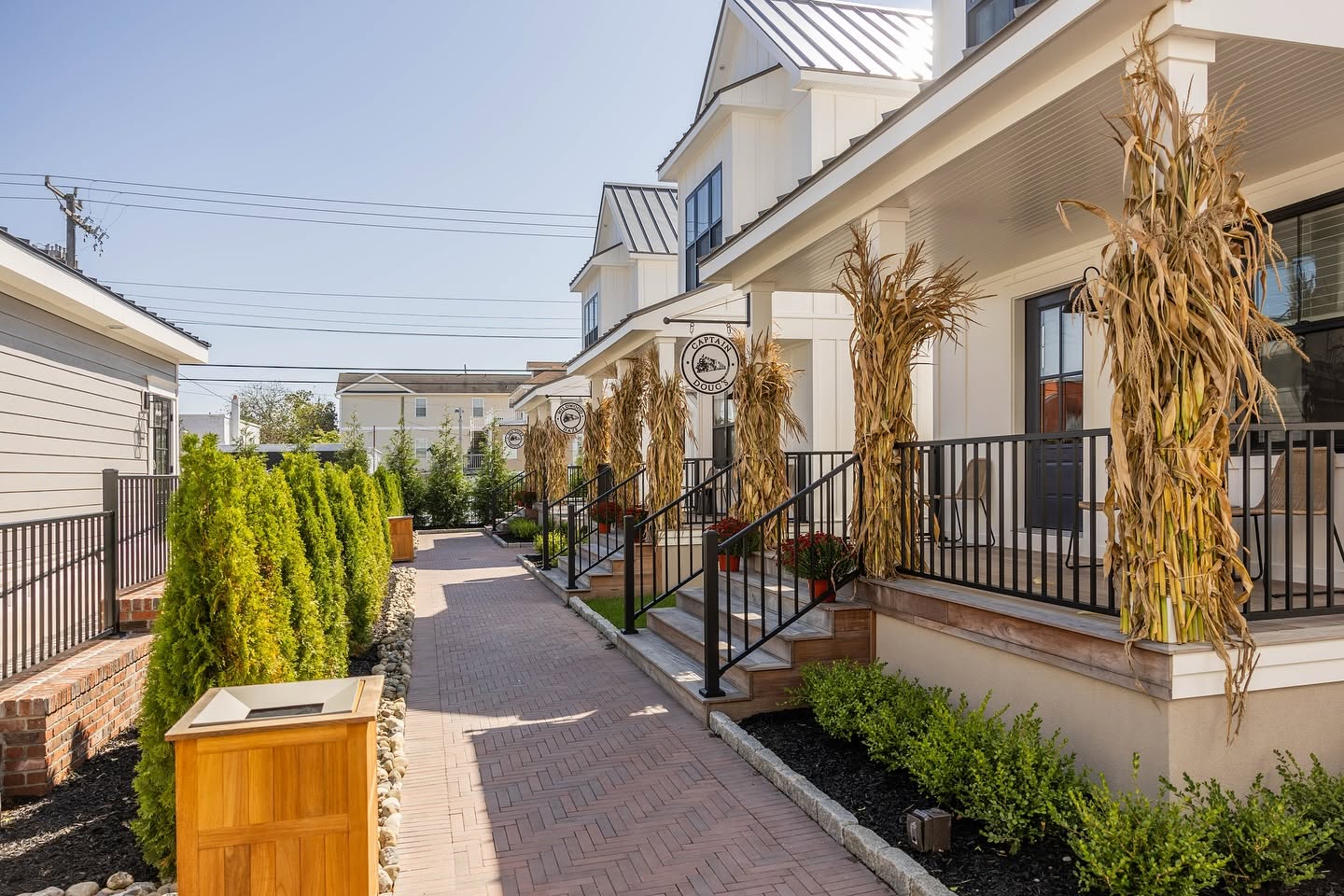 Brick walkway between the white farmhouse-style Hen Houses with autumn corn-stalk decorations